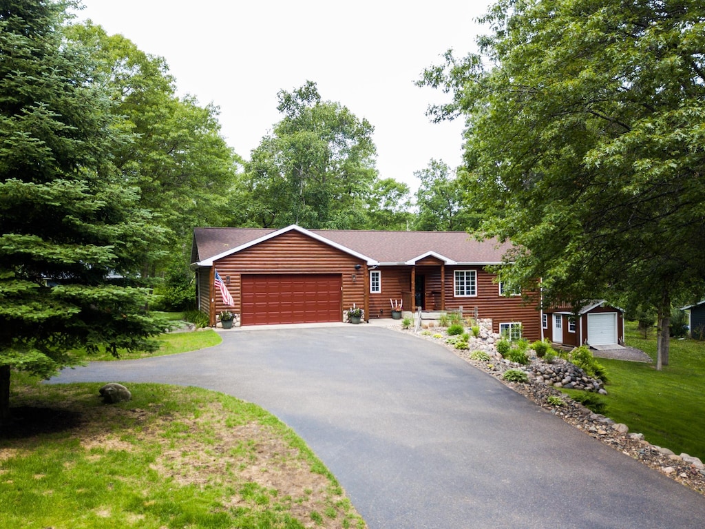30387 Spruce Dr, Breezy Point, MN 56472 - cabin with asphalt driveway, an attached garage, a front yard, and faux log siding