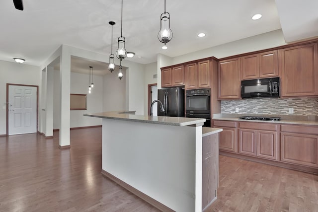 17417 72nd Ave N Unit 205, Maple Grove, MN 55311 - kitchen with black appliances, tasteful backsplash, light wood-style floors, a kitchen island with sink, and pendant lighting