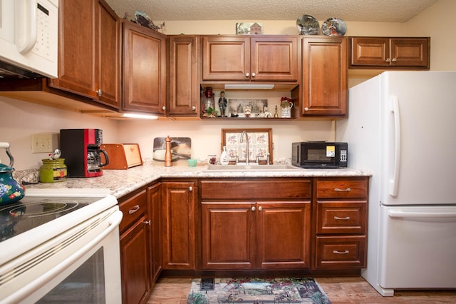 1415 Lake St Unit 114, Alexandria, MN 56308 - kitchen with white appliances, light wood finished floors, brown cabinetry, and a textured ceiling