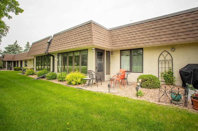 1415 Lake St Unit 114, Alexandria, MN 56308 - back of house featuring mansard roof, a yard, stucco siding, and roof with shingles