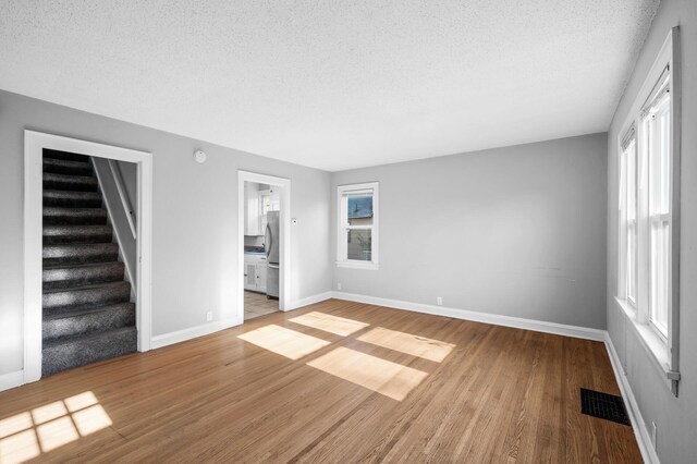 3806 Jackson St NE, Columbia Heights, MN 55421 - unfurnished living room with a textured ceiling, wood finished floors, and stairway