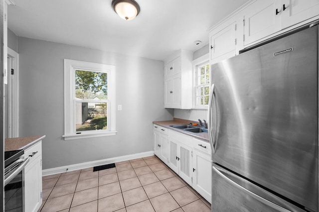 3806 Jackson St NE, Columbia Heights, MN 55421 - kitchen with freestanding refrigerator, stove, white cabinetry, light countertops, and light tile patterned flooring