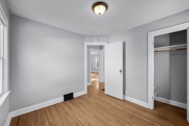 3806 Jackson St NE, Columbia Heights, MN 55421 - unfurnished bedroom featuring a closet, wood finished floors, and a textured ceiling