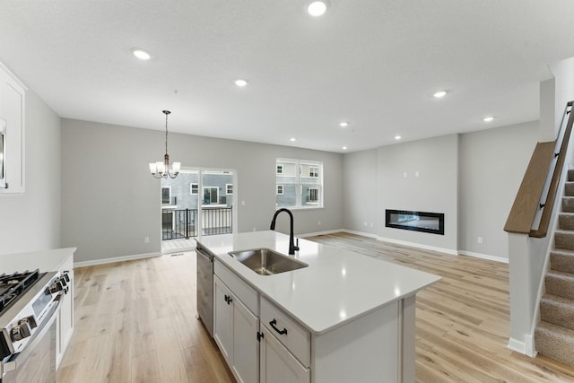 2720 Kepler Ave NE, Saint Michael, MN 55376 - kitchen with stainless steel appliances, light wood finished floors, a glass covered fireplace, light countertops, and an island with sink