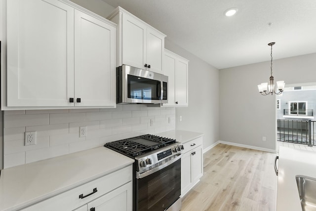 2720 Kepler Ave NE, Saint Michael, MN 55376 - kitchen featuring stainless steel appliances, light wood finished floors, decorative backsplash, a chandelier, and white cabinetry