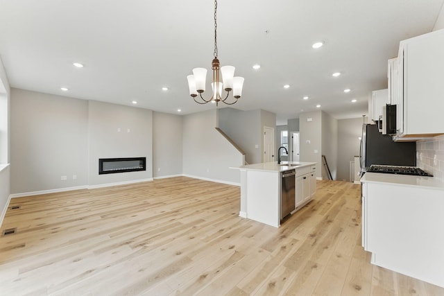 2720 Kepler Ave NE, Saint Michael, MN 55376 - kitchen with stainless steel appliances, white cabinetry, light wood-type flooring, a kitchen island with sink, and decorative light fixtures