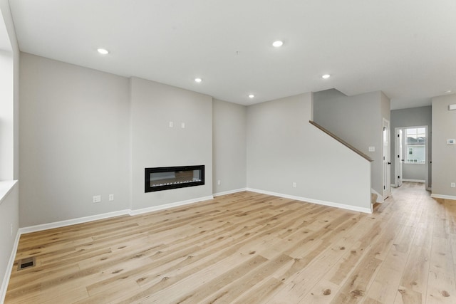 2720 Kepler Ave NE, Saint Michael, MN 55376 - unfurnished living room featuring light wood-type flooring, a glass covered fireplace, stairs, and recessed lighting