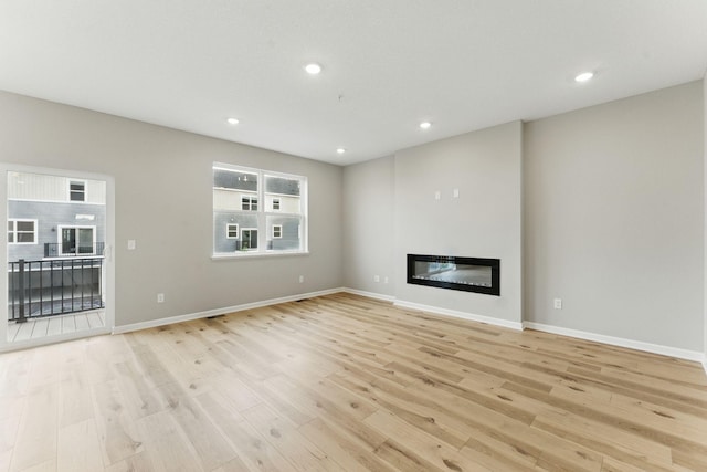 2720 Kepler Ave NE, Saint Michael, MN 55376 - unfurnished living room with a glass covered fireplace, light wood finished floors, and recessed lighting