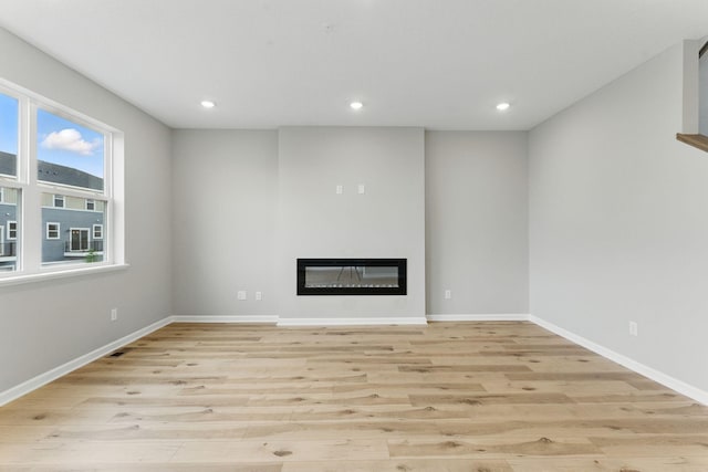 2720 Kepler Ave NE, Saint Michael, MN 55376 - unfurnished living room with light wood finished floors, a glass covered fireplace, and recessed lighting