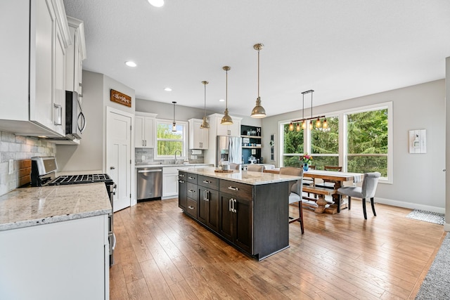 19550 Albany Cir NW, Elk River, MN 55330 - kitchen with stainless steel appliances, white cabinets, decorative backsplash, a center island, and pendant lighting