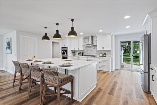 6901 Dawson Ln, Edina, MN 55435 - kitchen featuring wall chimney range hood, stainless steel appliances, light wood finished floors, white cabinetry, and recessed lighting