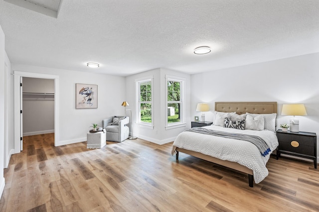 6901 Dawson Ln, Edina, MN 55435 - bedroom featuring light wood-style flooring, a textured ceiling, and a walk in closet