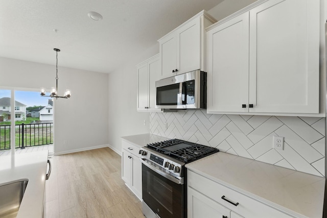 2726 Kepler Ave NE, Saint Michael, MN 55376 - kitchen with appliances with stainless steel finishes, a chandelier, tasteful backsplash, light countertops, and light wood-type flooring