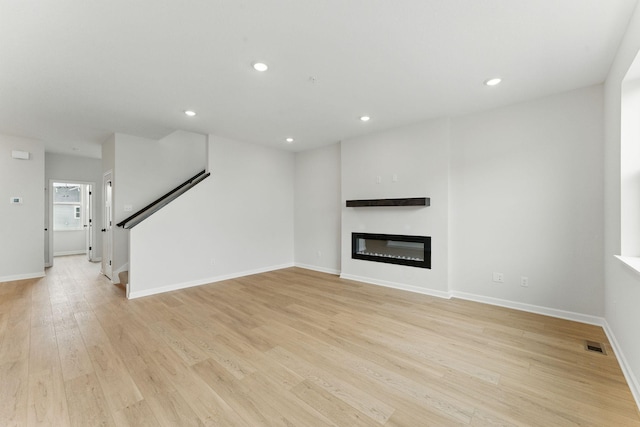2726 Kepler Ave NE, Saint Michael, MN 55376 - unfurnished living room with light wood-style floors, a glass covered fireplace, recessed lighting, and stairway