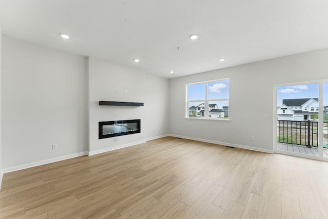 2726 Kepler Ave NE, Saint Michael, MN 55376 - unfurnished living room featuring a glass covered fireplace, light wood-style flooring, plenty of natural light, and recessed lighting