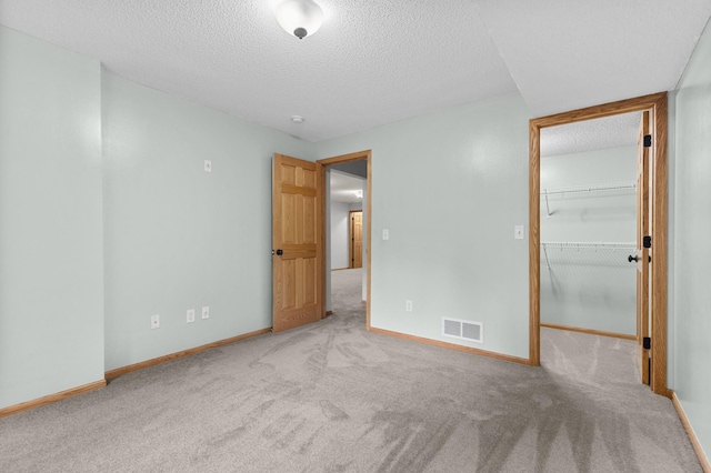 1437 131st Dr NE, Blaine, MN 55449 - unfurnished bedroom with a textured ceiling, carpet flooring, a walk in closet, and a closet