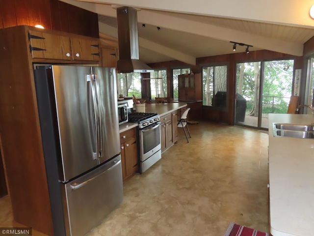 9429 Jeske Ave NW, Corinna Twp, MN 55302 - kitchen featuring appliances with stainless steel finishes, wall chimney range hood, light floors, brown cabinets, and plenty of natural light