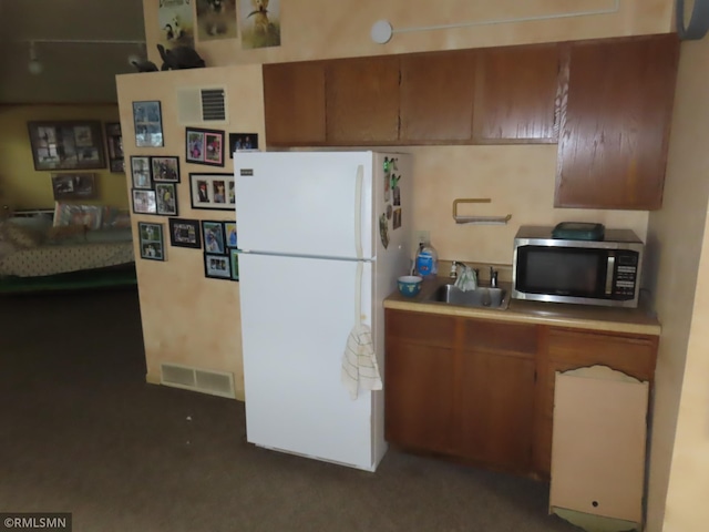 9429 Jeske Ave NW, Corinna Twp, MN 55302 - kitchen featuring stainless steel microwave, freestanding refrigerator, brown cabinetry, and dark carpet