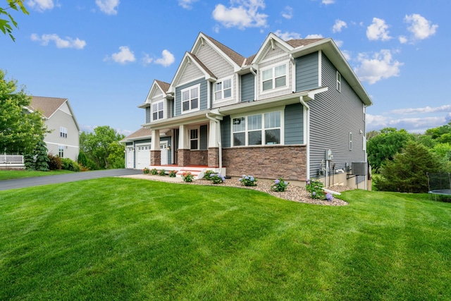 9721 Emerson Ct, Eden Prairie, MN 55347 - craftsman house featuring a trampoline, driveway, an attached garage, a front yard, and stone siding