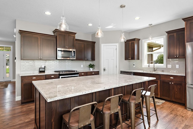 14675 77th St NE, Otsego, MN 55330 - kitchen featuring appliances with stainless steel finishes, dark wood-style flooring, a kitchen island, decorative backsplash, and recessed lighting