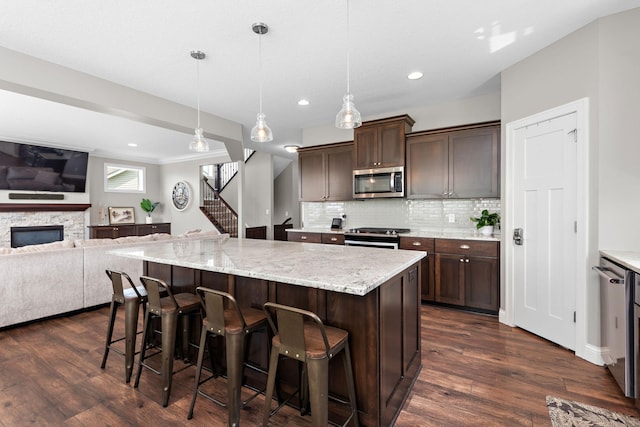 14675 77th St NE, Otsego, MN 55330 - kitchen featuring appliances with stainless steel finishes, decorative backsplash, dark brown cabinets, dark wood-style floors, and a kitchen breakfast bar
