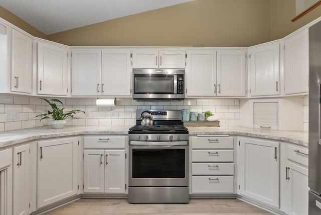 5278 River Wood Dr, Savage, MN 55378 - kitchen featuring appliances with stainless steel finishes, vaulted ceiling, white cabinetry, and backsplash