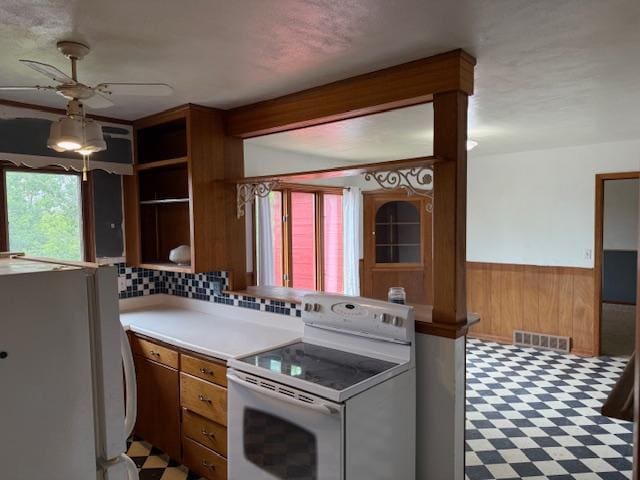 103 Circle Dr, Jackson, MN 56143 - kitchen with white appliances, a ceiling fan, wooden walls, a wainscoted wall, and light countertops
