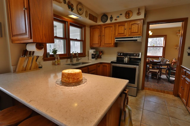 1138 Wintergreen Ln NE, Bemidji, MN 56601 - kitchen with stainless steel electric stove, under cabinet range hood, a peninsula, light countertops, and brown cabinetry