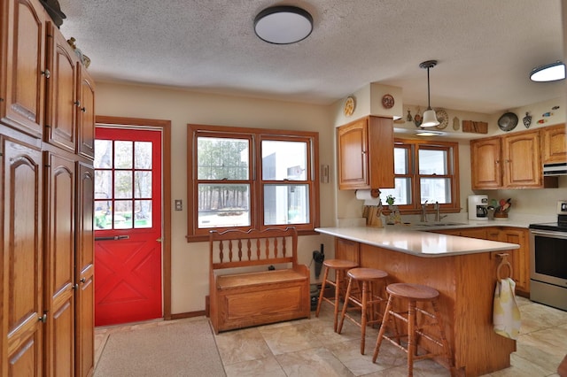 1138 Wintergreen Ln NE, Bemidji, MN 56601 - kitchen featuring stainless steel electric range, a peninsula, a kitchen breakfast bar, ventilation hood, and light countertops