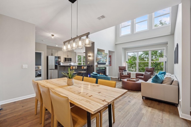 1020 Portland Ave, Minneapolis, MN 55404 - dining room featuring wood finished floors, a towering ceiling, and a warm lit fireplace