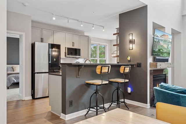 1020 Portland Ave, Minneapolis, MN 55404 - kitchen featuring appliances with stainless steel finishes, a breakfast bar area, light wood-type flooring, and a peninsula