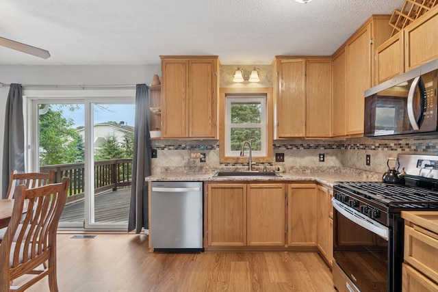 1650 107th Ave NW, Coon Rapids, MN 55433 - kitchen with appliances with stainless steel finishes, backsplash, plenty of natural light, light wood-type flooring, and a textured ceiling