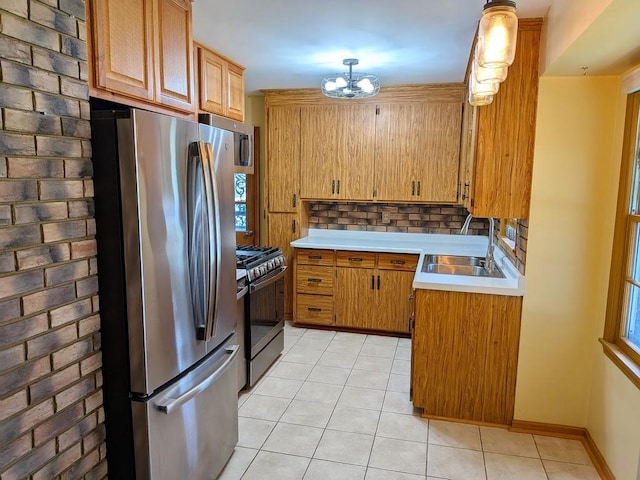 3465 5th St NE, Minneapolis, MN 55418 - kitchen with stainless steel appliances, light tile patterned floors, light countertops, a chandelier, and brown cabinets