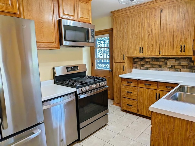 3465 5th St NE, Minneapolis, MN 55418 - kitchen with stainless steel appliances, light countertops, light tile patterned floors, brown cabinets, and decorative backsplash