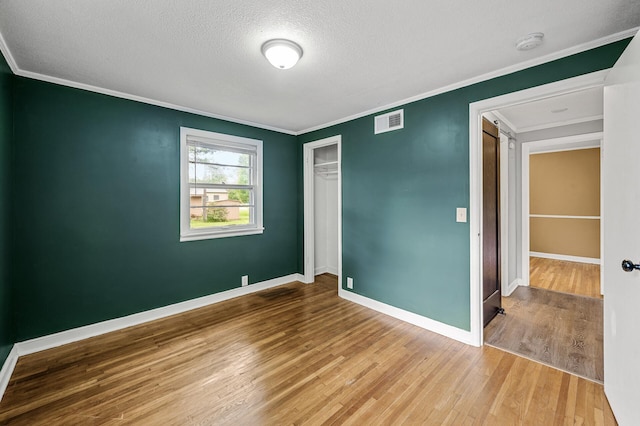 6289 Edgewood Ave N, Brooklyn Park, MN 55428 - unfurnished bedroom featuring wood finished floors, crown molding, a textured ceiling, and a closet