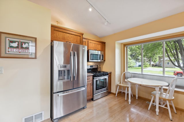 3147 94th Ln NE, Blaine, MN 55449 - kitchen featuring stainless steel appliances, rail lighting, brown cabinetry, light wood finished floors, and decorative backsplash