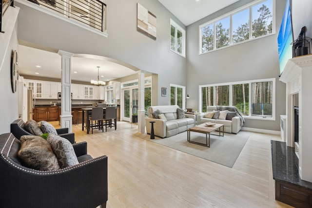 26659 145th St NW, Zimmerman, MN 55398 - living area with ornate columns, a high ceiling, arched walkways, a chandelier, and light wood-style flooring