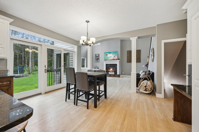 26659 145th St NW, Zimmerman, MN 55398 - dining room with light wood-style flooring, a glass covered fireplace, a chandelier, decorative columns, and a textured ceiling