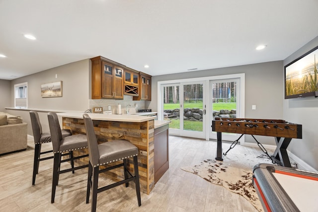 26659 145th St NW, Zimmerman, MN 55398 - kitchen featuring brown cabinetry, light wood finished floors, recessed lighting, glass insert cabinets, and a peninsula