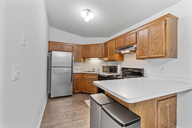 14258 Towers Ln, Eden Prairie, MN 55347 - kitchen featuring appliances with stainless steel finishes, under cabinet range hood, a peninsula, light countertops, and a textured ceiling