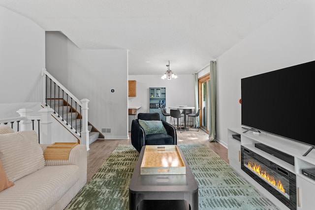 14258 Towers Ln, Eden Prairie, MN 55347 - living area with light wood-style floors, stairs, a chandelier, and a glass covered fireplace
