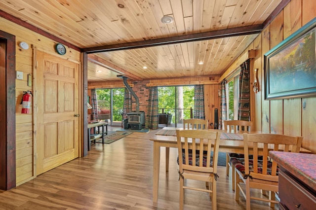 43784 Spider Lake Rd, Marcell, MN 56657 - dining area featuring a wood stove, wood walls, a wood ceiling with exposed beams, and wood finished floors