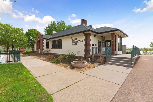 5043 42nd Ave S, Minneapolis, MN 55417 - view of front of home featuring covered porch, a chimney, brick siding, roof with shingles, and stucco siding