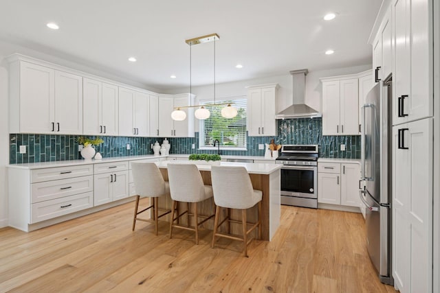 5043 42nd Ave S, Minneapolis, MN 55417 - kitchen featuring stainless steel appliances, wall chimney exhaust hood, a kitchen bar, white cabinetry, and recessed lighting