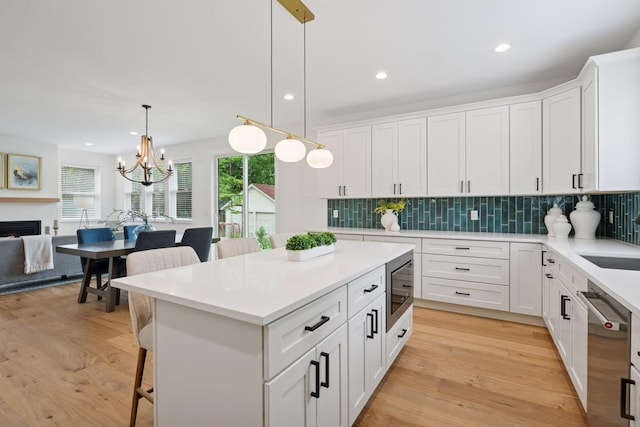 5043 42nd Ave S, Minneapolis, MN 55417 - kitchen with appliances with stainless steel finishes, a kitchen breakfast bar, backsplash, light wood finished floors, and white cabinetry