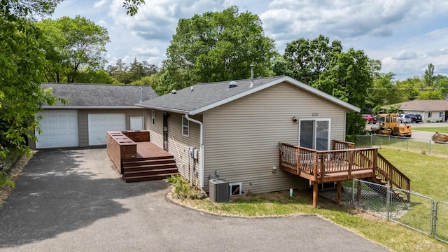 1731 Park Ave NW, Bemidji, MN 56601 - back of property featuring a wooden deck, roof with shingles, a garage, and asphalt driveway