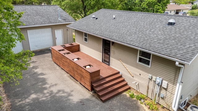 1731 Park Ave NW, Bemidji, MN 56601 - rear view of property featuring roof with shingles, a wooden deck, driveway, and a garage