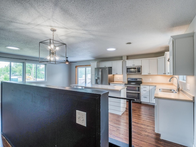 1731 Park Ave NW, Bemidji, MN 56601 - kitchen featuring stainless steel appliances, dark wood finished floors, a textured ceiling, light countertops, and pendant lighting