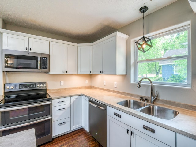 1731 Park Ave NW, Bemidji, MN 56601 - kitchen featuring appliances with stainless steel finishes, light countertops, white cabinetry, and hanging light fixtures