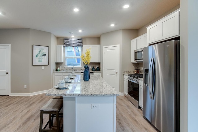 6574 208th St W, Farmington, MN 55024 - kitchen with appliances with stainless steel finishes, light wood-style floors, a kitchen island, a kitchen bar, and recessed lighting